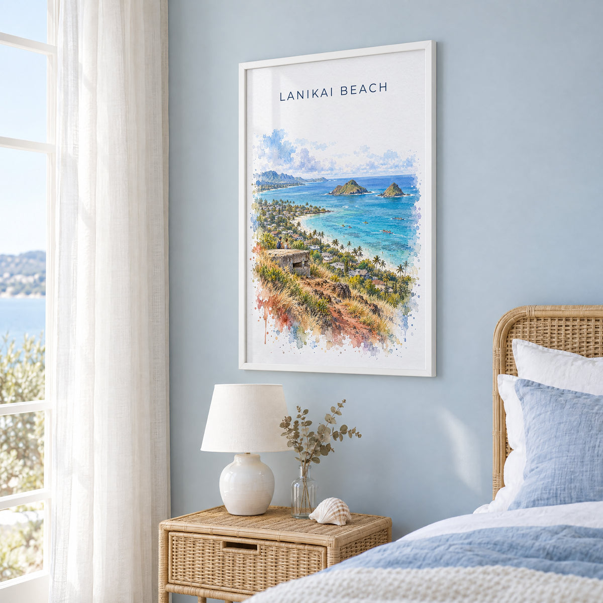 Lanikai Beach watercolor print in a white frame on a pale blue wall beside a rattan bed in a coastal bedroom