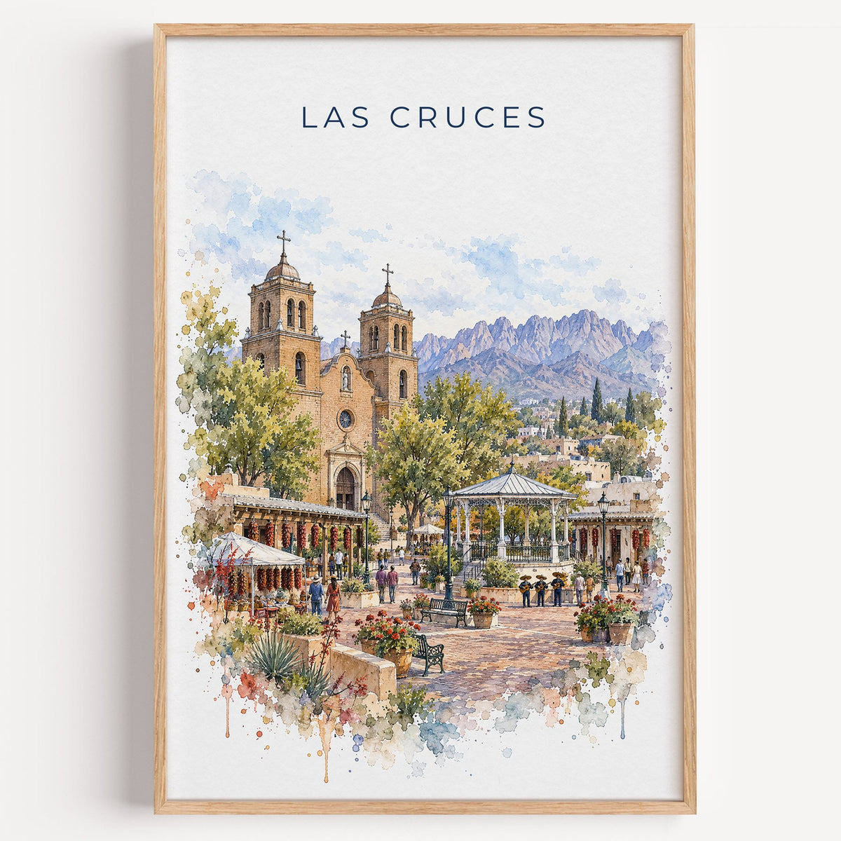 Las Cruces watercolor print in a light oak frame on a plain white wall