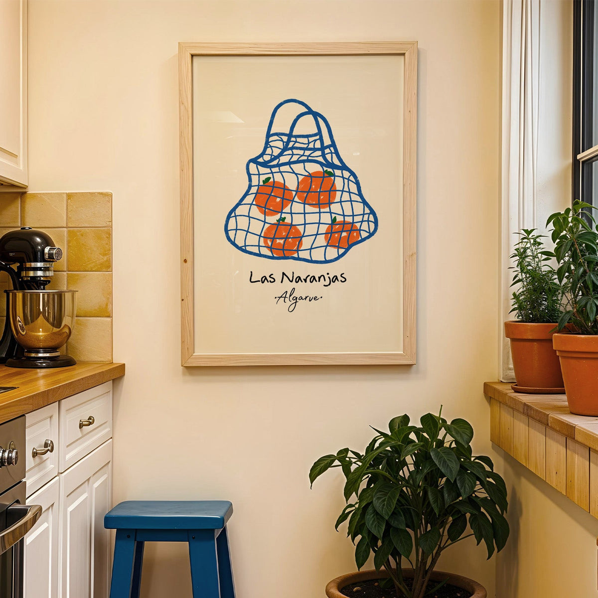 Las naranjas orange net bag print in a wood frame on a yellow tiled kitchen wall