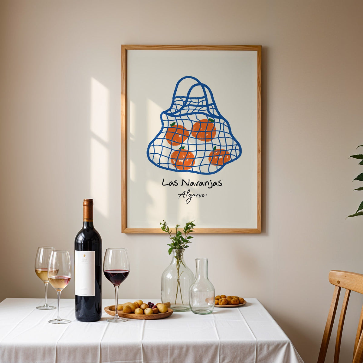 Las naranjas orange net bag print in an oak frame above a table laid with red wine