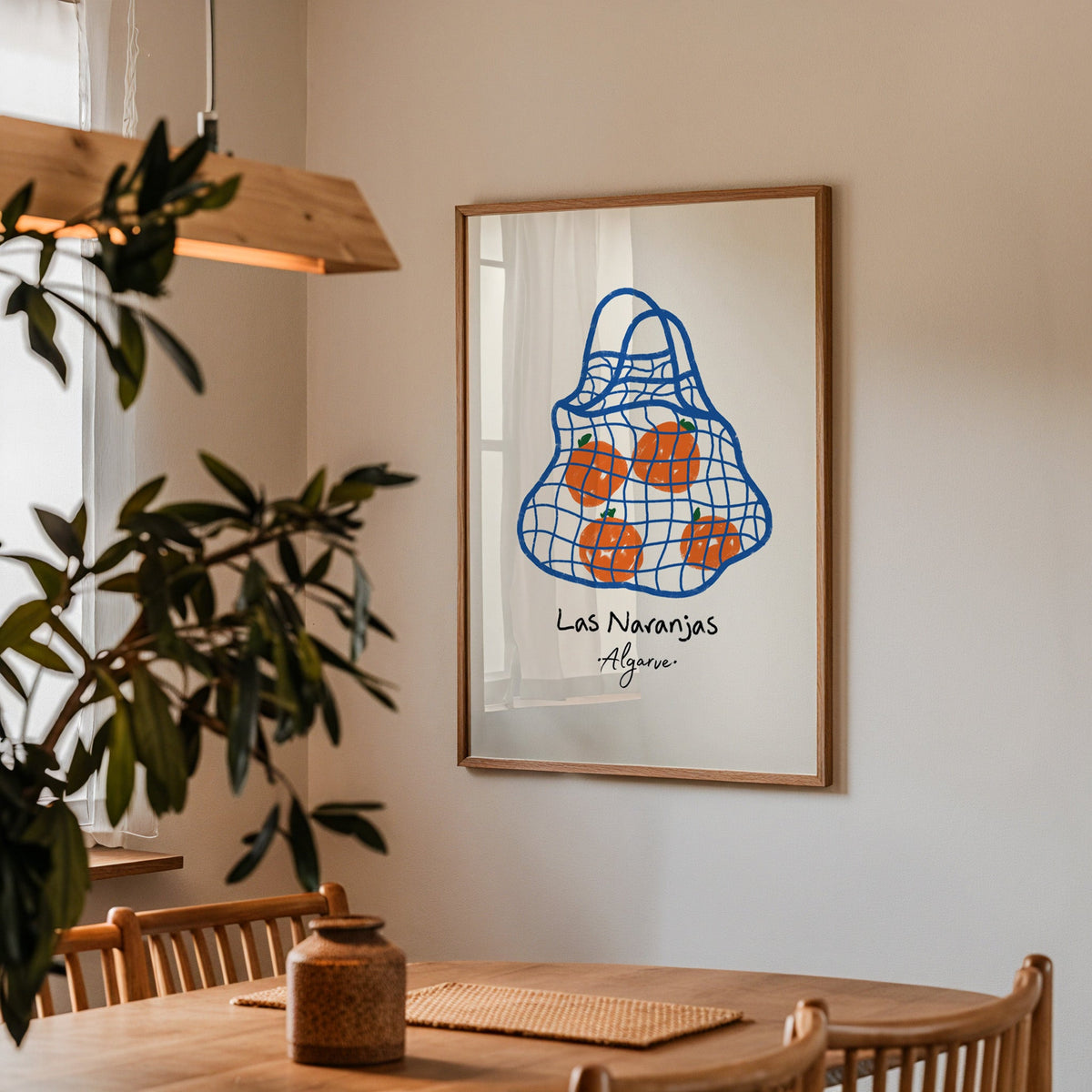 Las naranjas orange net bag print in a walnut frame above a table beside an olive tree