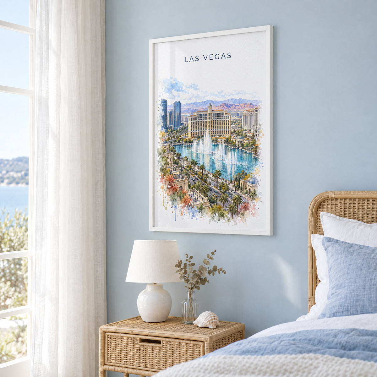 Las Vegas watercolor print in a white frame on a pale blue wall beside a rattan bed in a coastal bedroom
