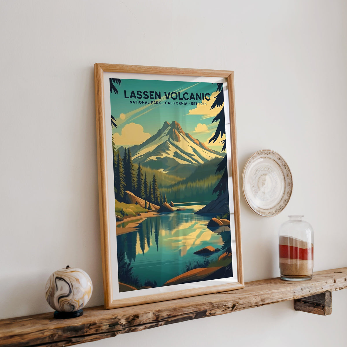 Lassen Volcanic National Park print in an oak frame on a wood shelf with ceramics and a sand-filled jar