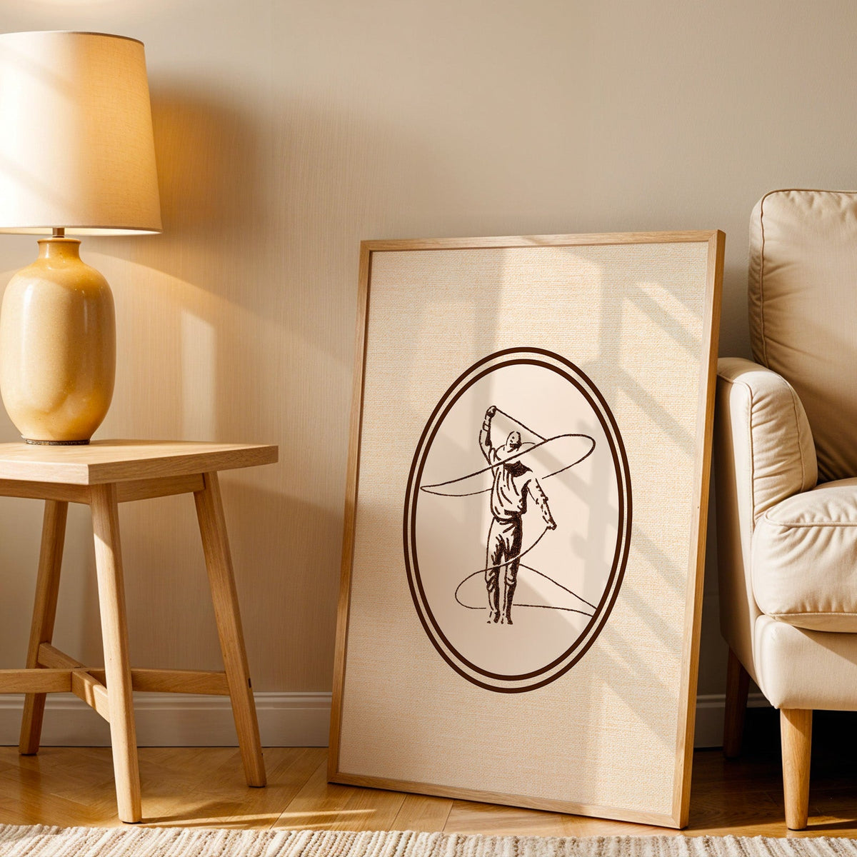 Lasso cowboy oval print in an oak frame beside an amber ceramic lamp