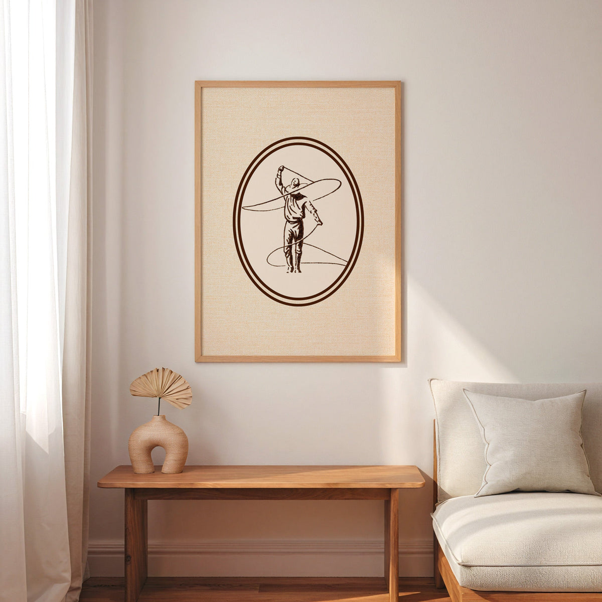 Lasso cowboy oval print in an oak frame above a console with an arch vase