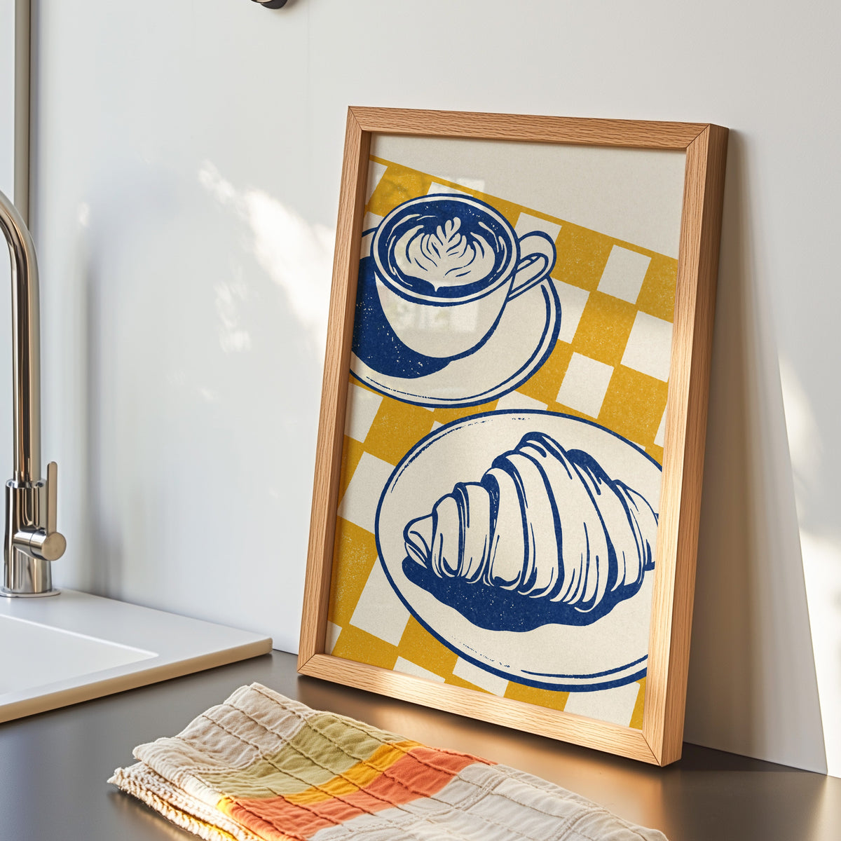 Latte and croissant print in an oak frame by the kitchen sink beside a striped tea towel