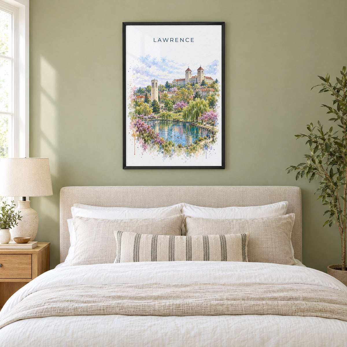 Lawrence, Kansas watercolor print in a black frame above an upholstered headboard in a sage green bedroom