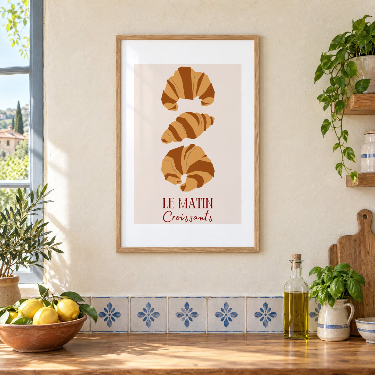 LE MATIN Croissants caramel trio print in an oak frame on a cream plaster wall above a worktop with a bowl of lemons and blue-and-white tiles