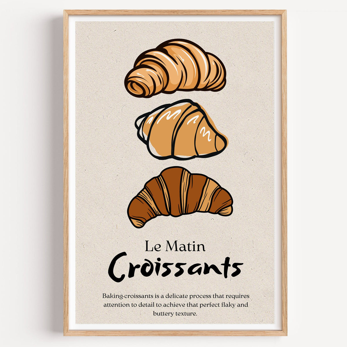 Le Matin Croissants three croissants print in a light oak frame on a plain white wall