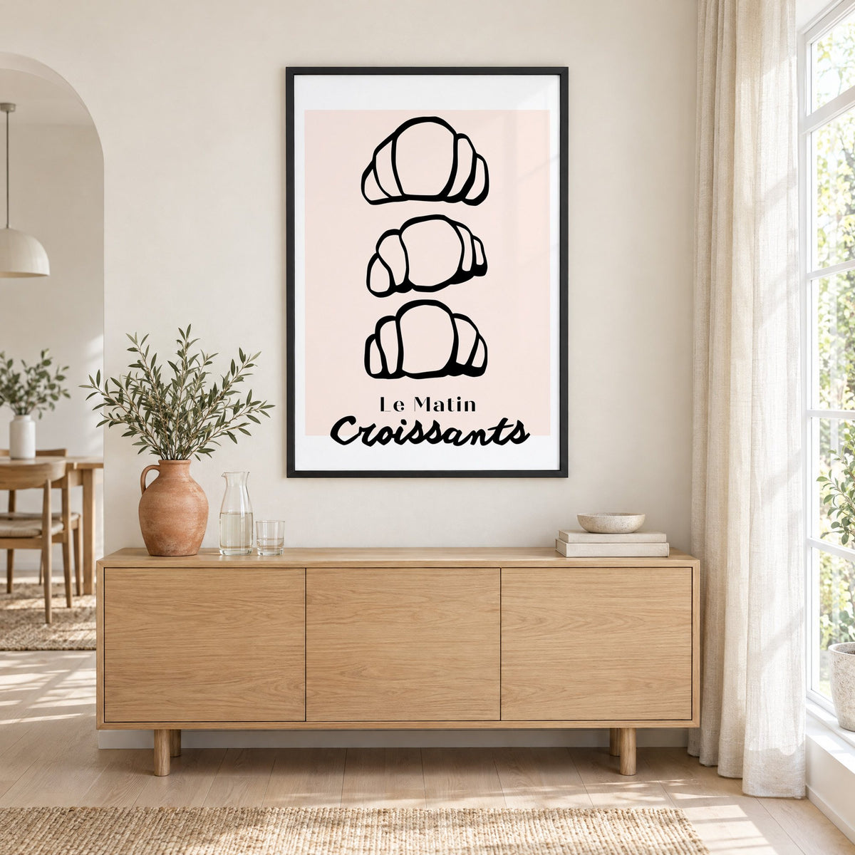 Le Matin black outline croissants print in a black frame above an oak sideboard with a terracotta vase of olive branches