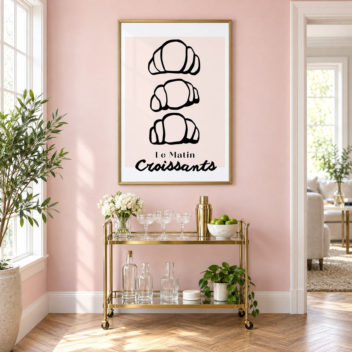 Le Matin black outline croissants print in a brass frame above a gold bar cart on a blush pink wall
