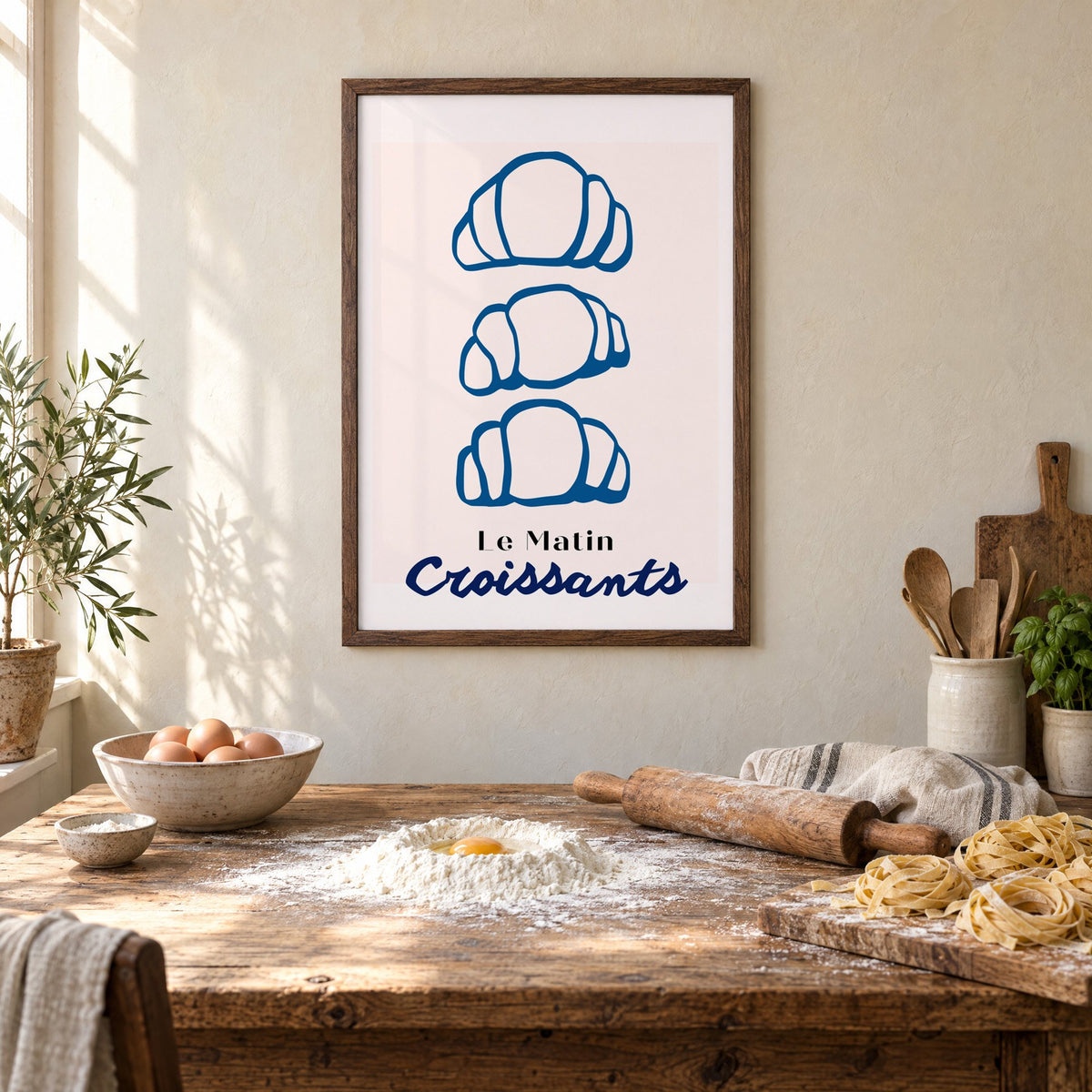 Le Matin blue croissants print in a walnut frame above a rustic table set for making fresh pasta