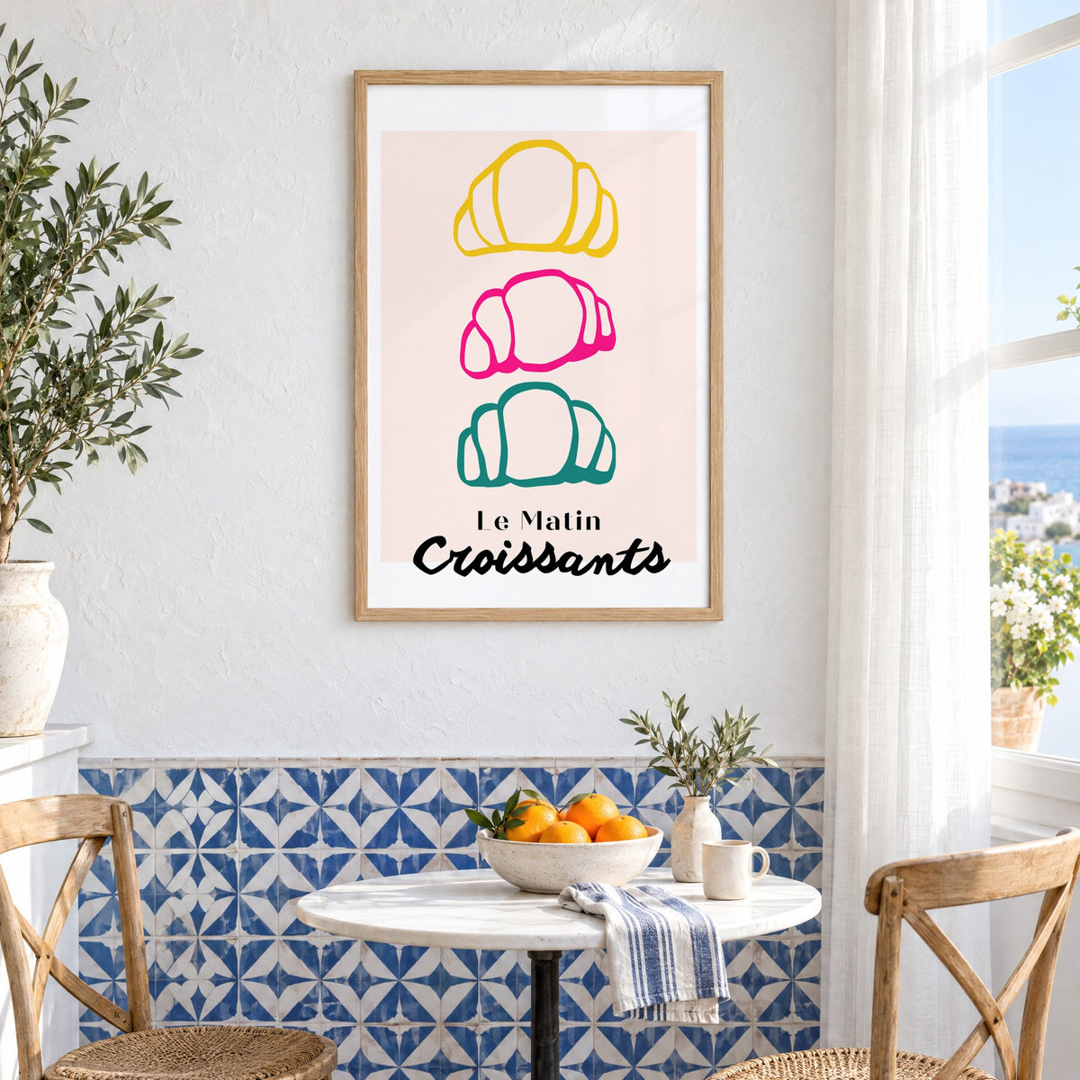 Le Matin colorful croissants print in an oak frame above a bistro table and blue patterned tiles
