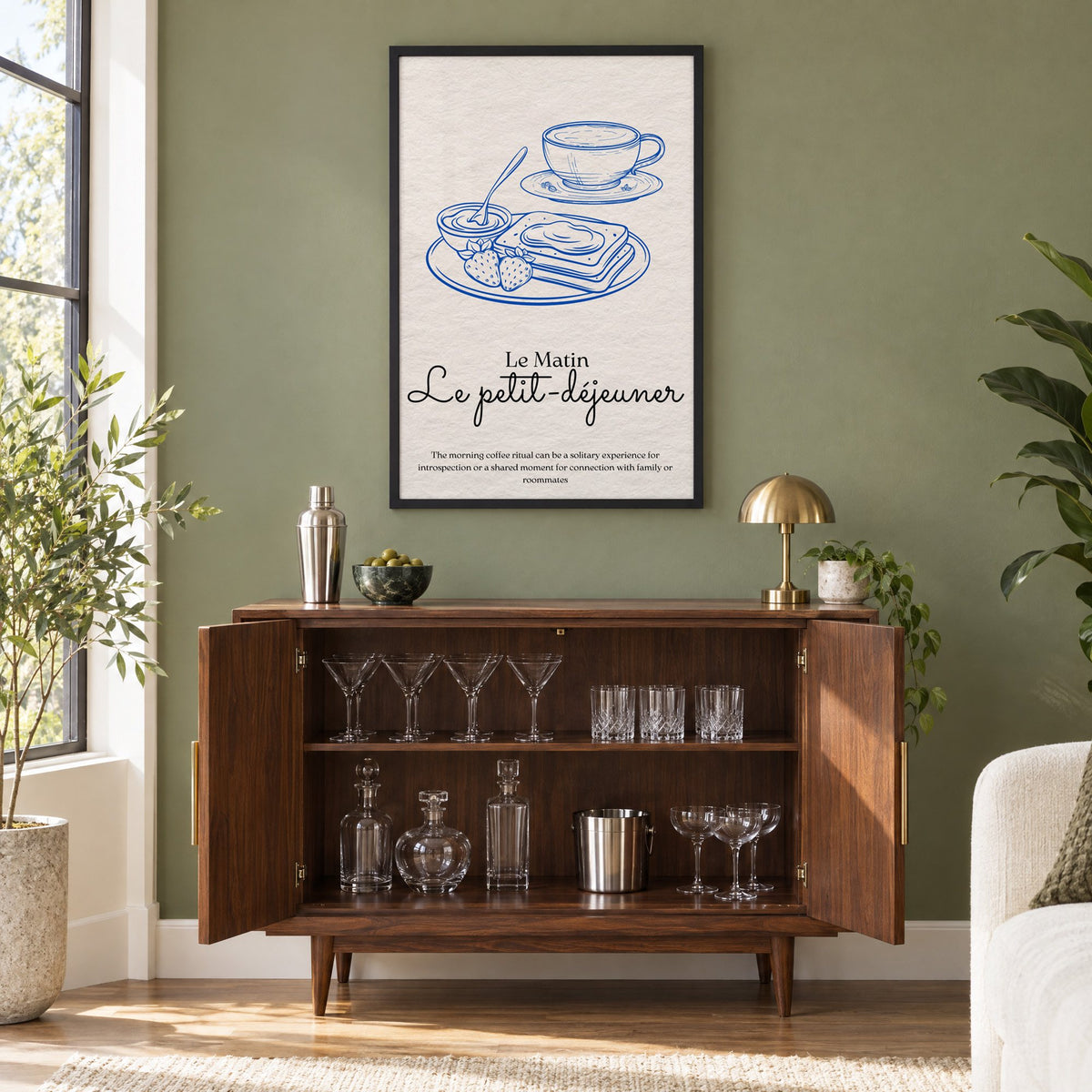 Le petit-dejeuner cobalt engraved breakfast print in a black frame on an olive green wall above a walnut bar cabinet with glassware