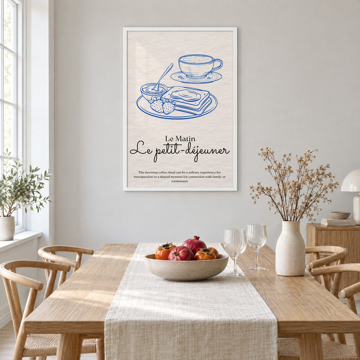 Le petit-dejeuner cobalt engraved breakfast print in a white frame above a light oak dining table with a linen runner and fruit bowl