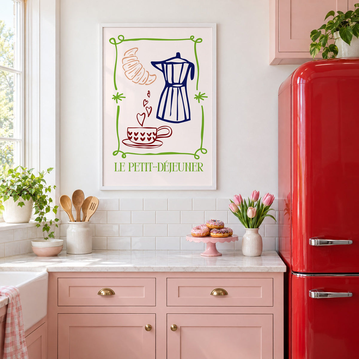 LE PETIT-DÉJEUNER moka pot and croissant print in a white frame above pink cabinets beside a red retro fridge