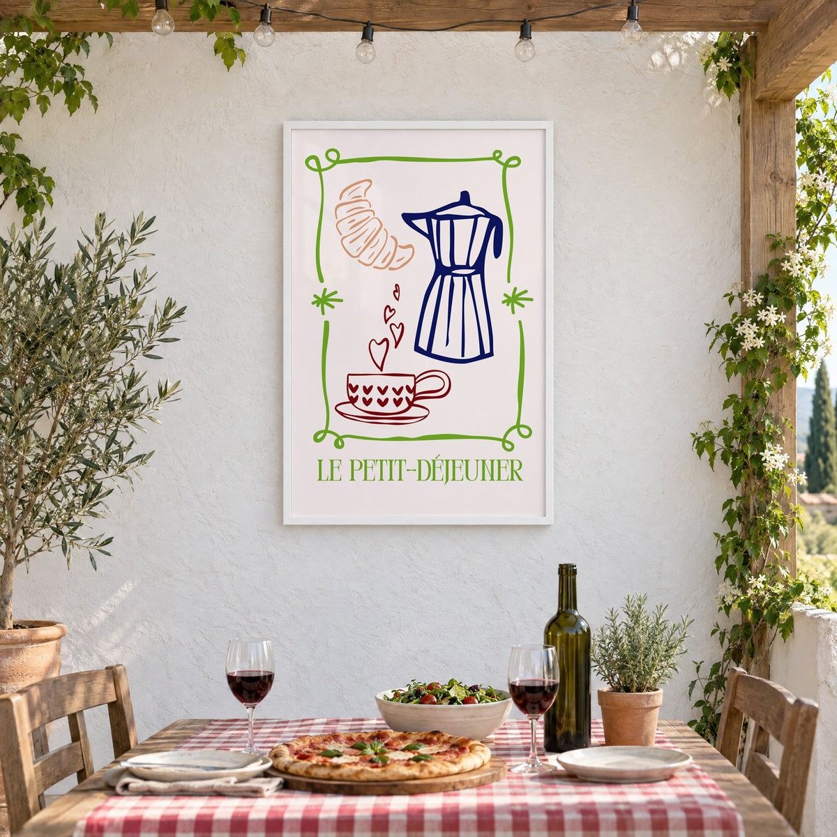 LE PETIT-DÉJEUNER moka pot and croissant print in a white frame on a stucco wall above a checked-cloth table with pizza and red wine