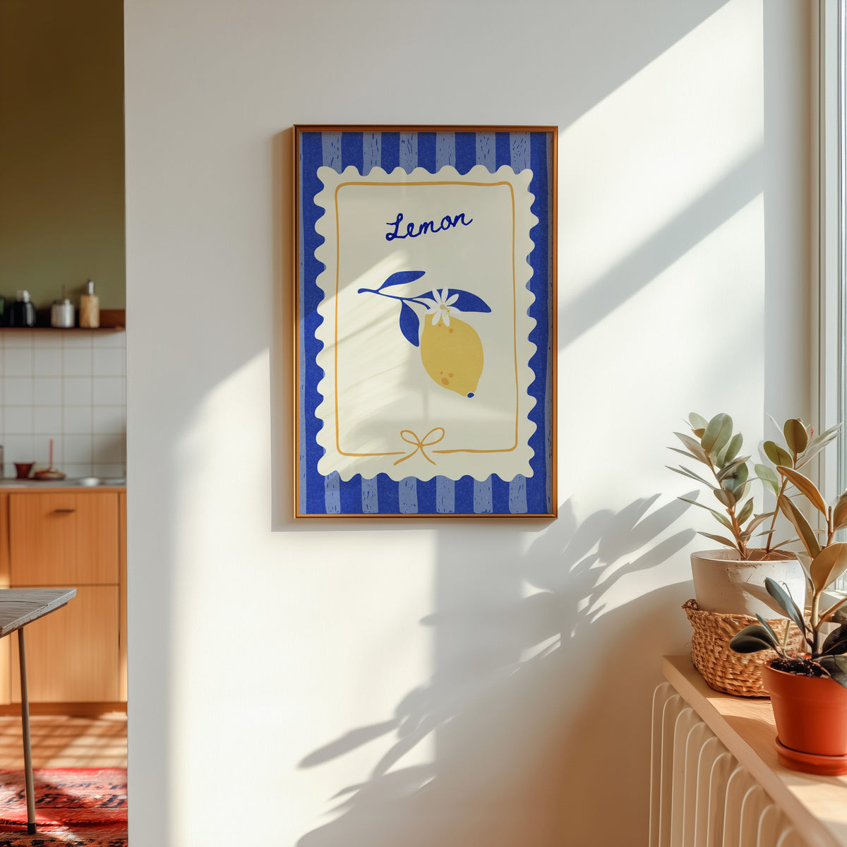 Lemon branch print in a gold frame in sunlight with plants and a kitchen beyond