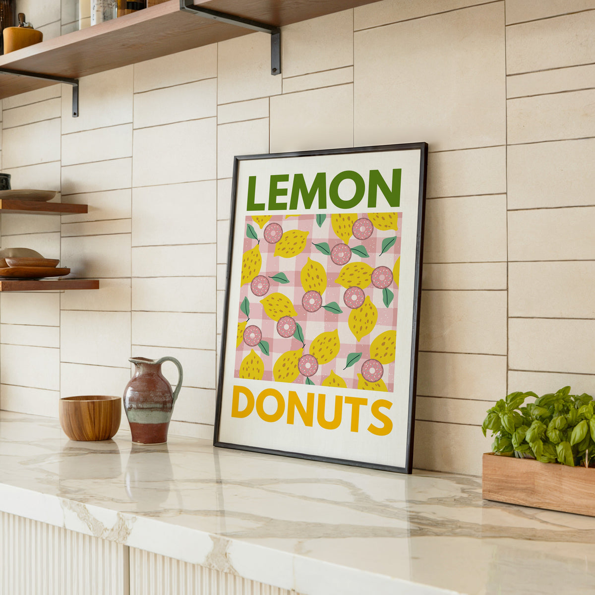Lemon and donuts print in a black frame leaning on a marble counter in a tiled kitchen