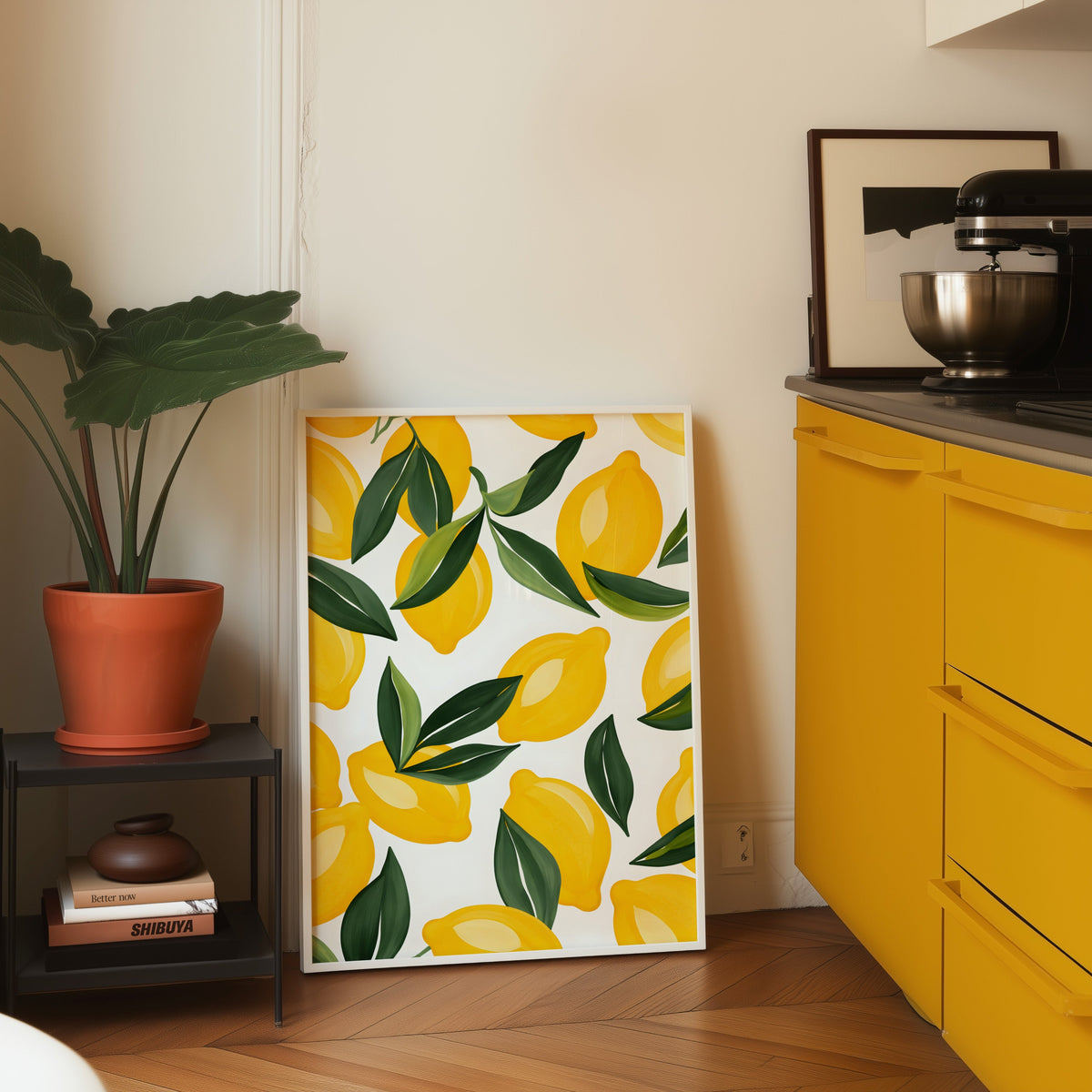 Lemon pattern print in a white frame leaning on parquet beside a yellow kitchen