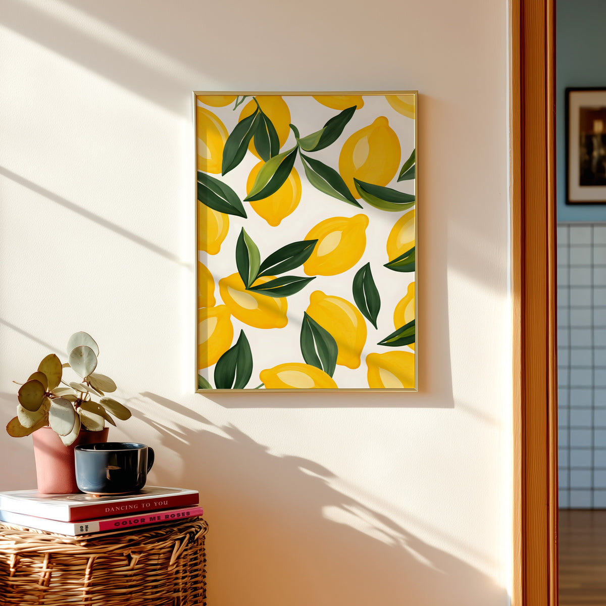 Lemon pattern print in a gold frame above a basket of books and a pilea plant