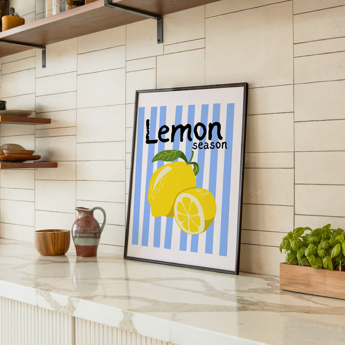 Lemon Season print in a black frame leaning on a marble counter in a tiled kitchen