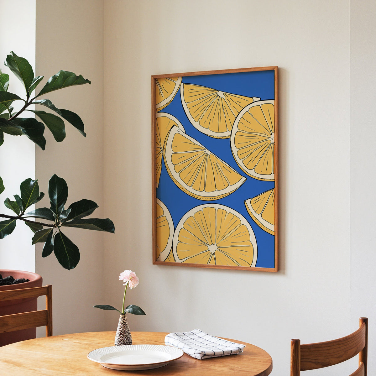 Lemon slice pattern print in a walnut frame above a round table beside a fiddle-leaf fig