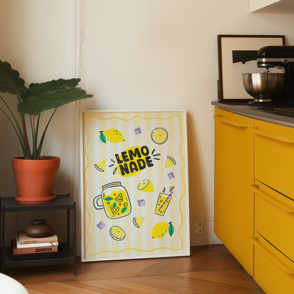 Lemonade print in a white frame leaning on parquet beside a bright yellow kitchen