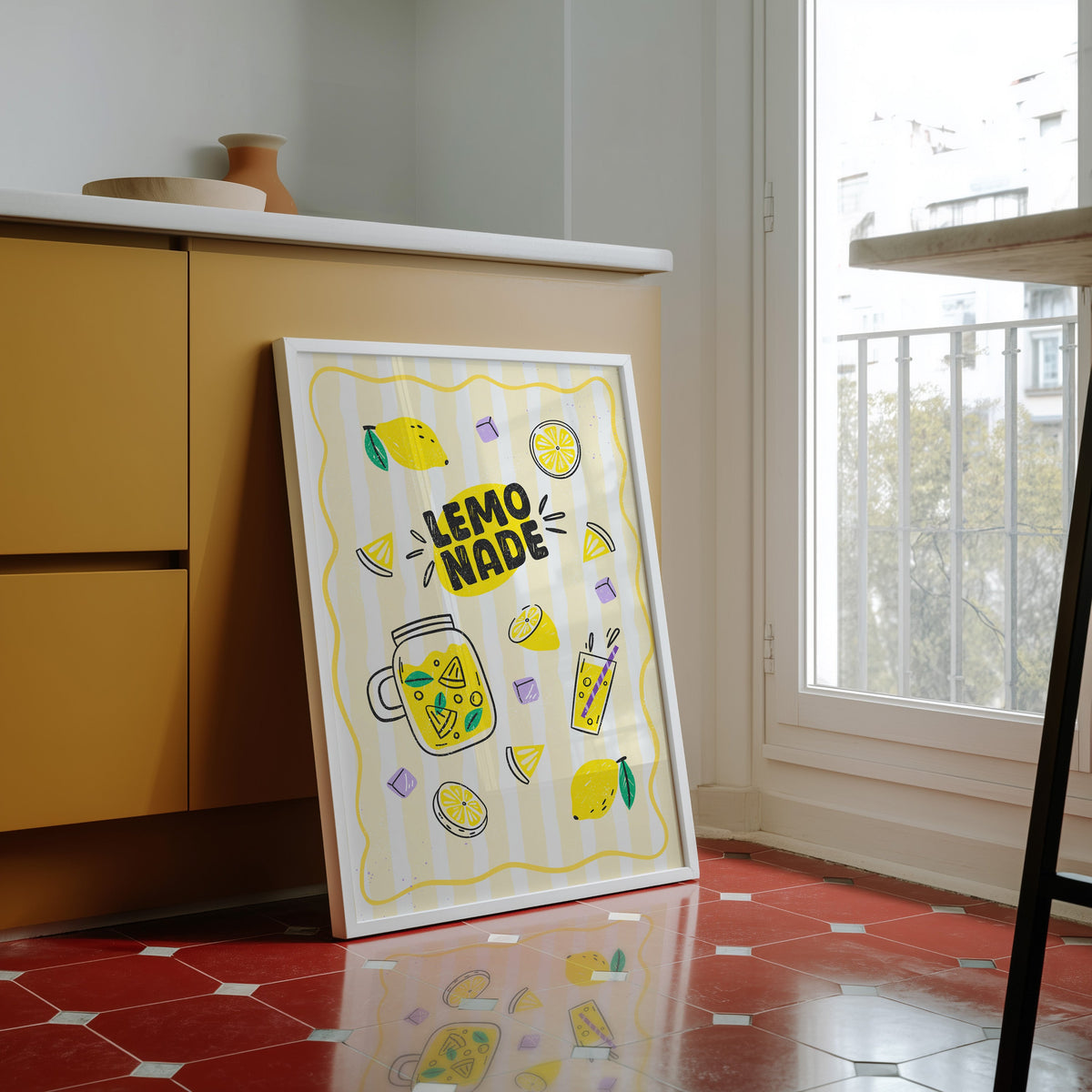 Lemonade print in a white frame against yellow cabinets on a red tiled floor