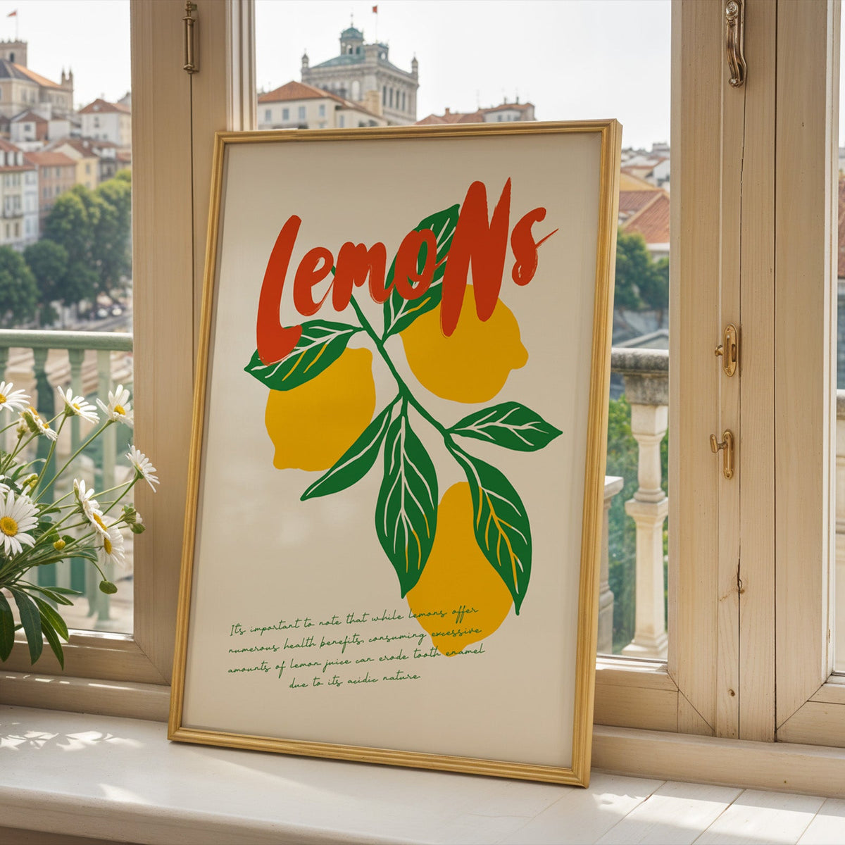 Lemon branch print in a gold frame on a window sill overlooking a hillside town