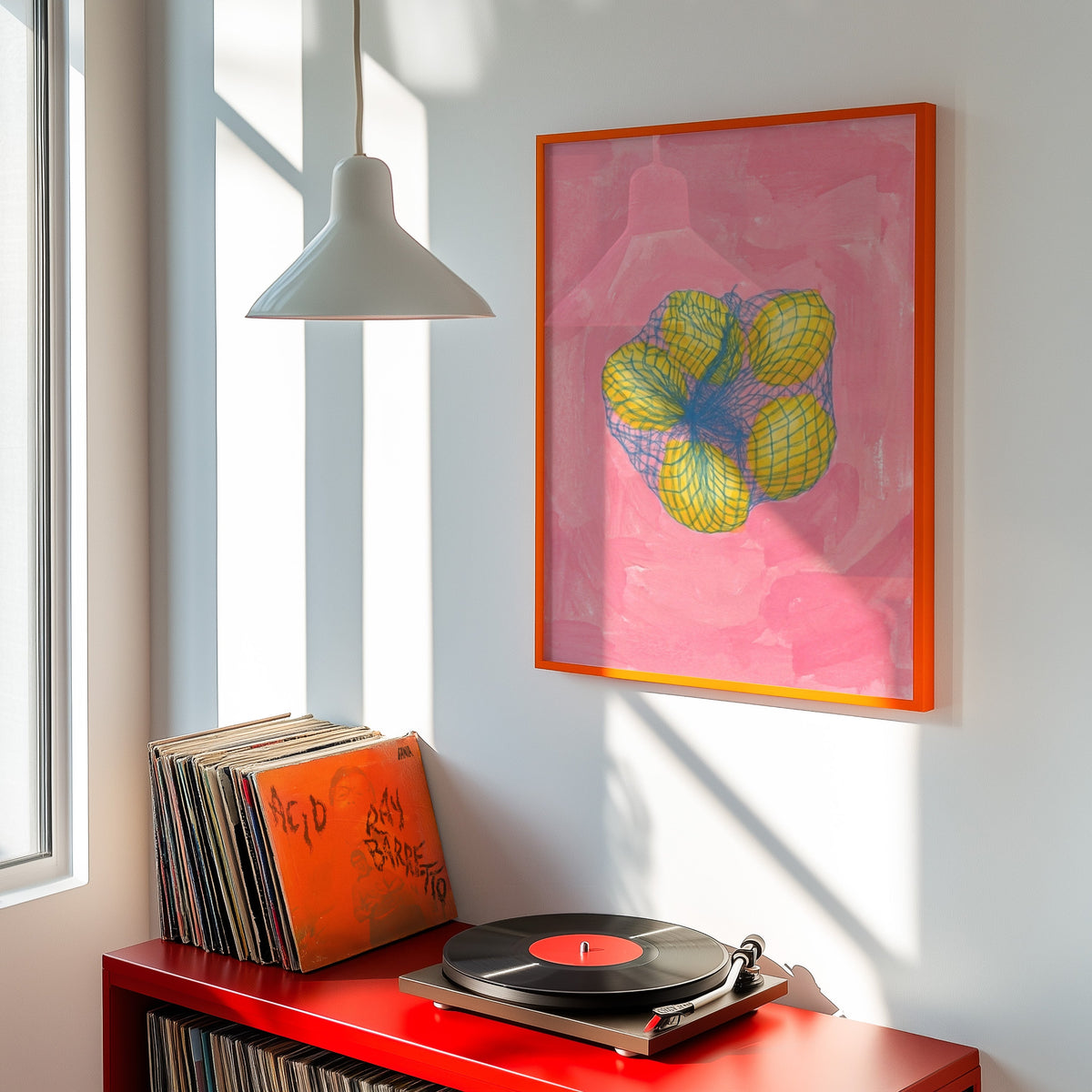 Pink lemon wall art print shown in an orange frame above a red record cabinet and turntable