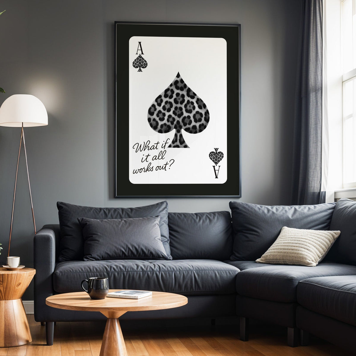 Leopard fur ace of spades card print in a black frame above a charcoal sofa on a grey wall