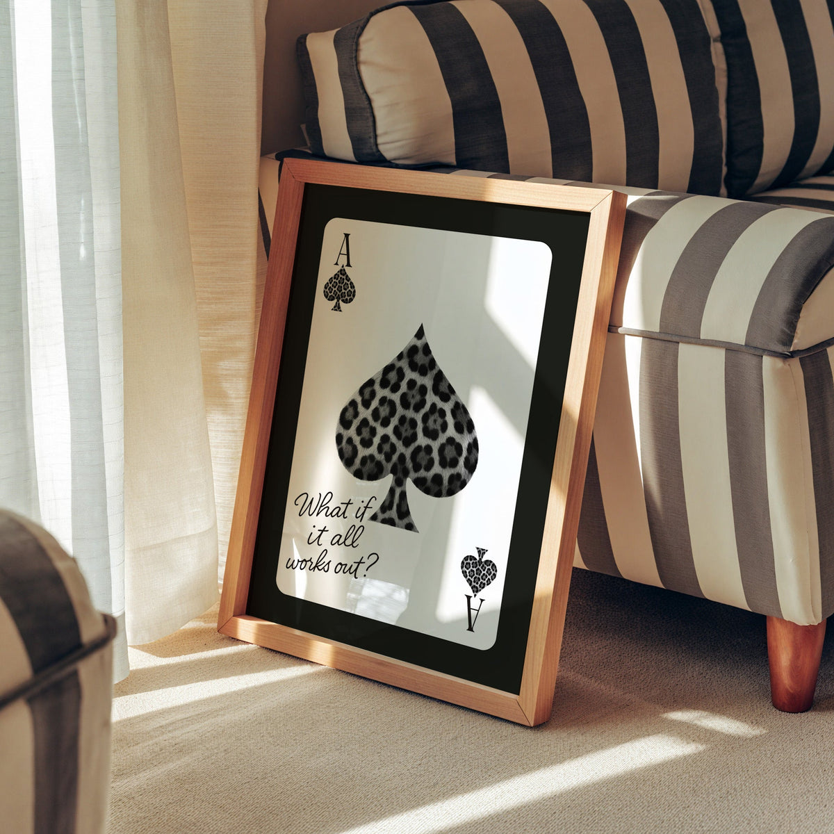 Leopard fur ace of spades card print in a pine frame leaning against a striped armchair