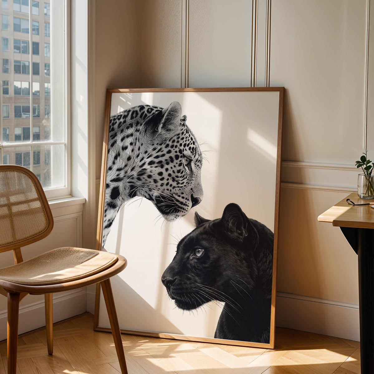 Leopard and black panther facing each other print in an oak frame leaning in a sunlit corner beside a cane chair