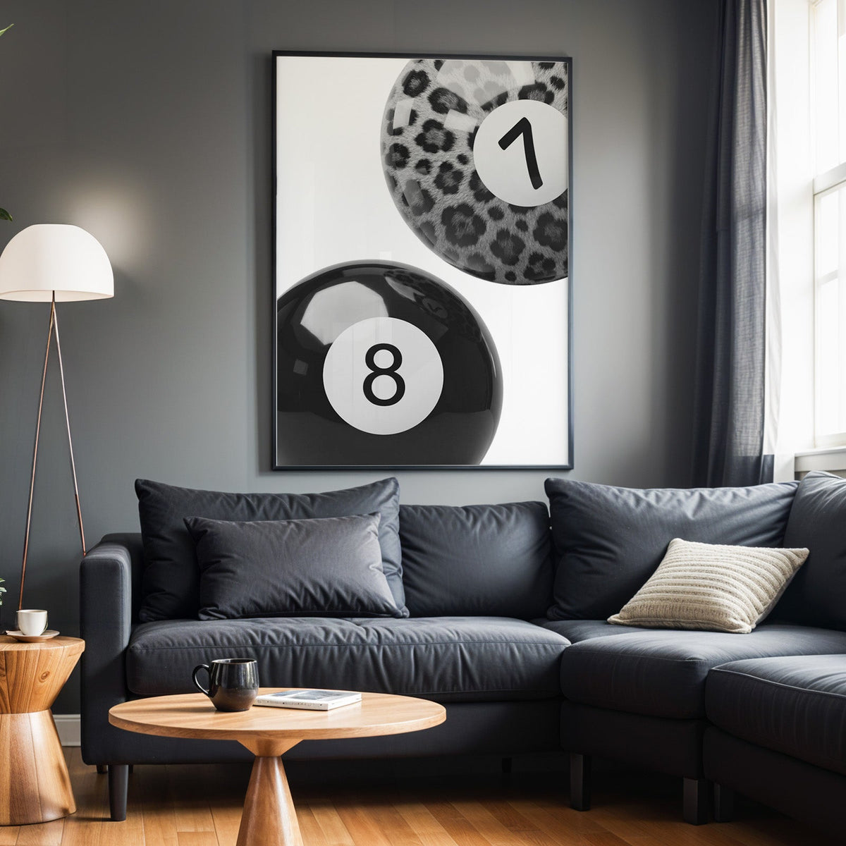 Leopard fur seven ball and black eight ball print in a black frame above a charcoal sofa on a grey wall