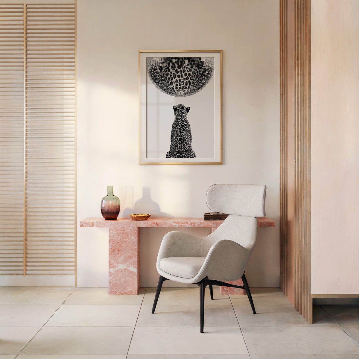 Leopard looking up at giant disco ball print shown in a gold frame above a pink marble console and armchair