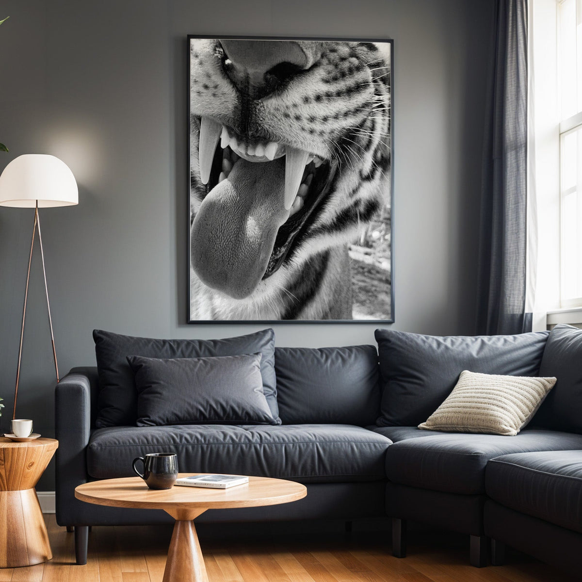 Big cat fangs and tongue macro black and white print in a black frame above a charcoal sofa on a grey wall