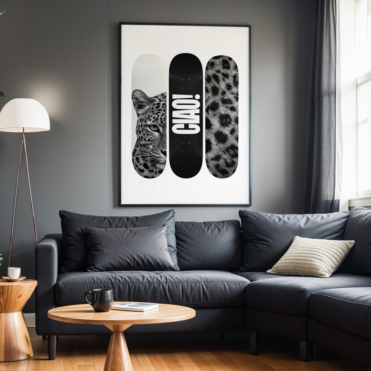 Three skateboard decks with leopard face and CIAO print in a black frame above a charcoal sofa on a grey wall