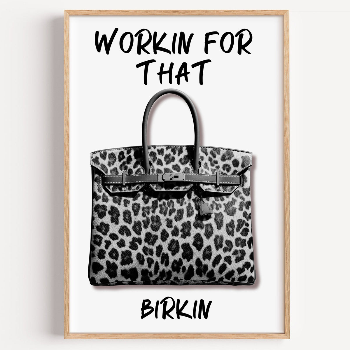 Leopard fur structured handbag with brush lettering print in a light oak frame on a plain white wall