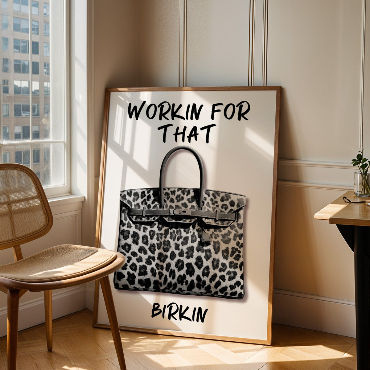 Leopard fur structured handbag with brush lettering print in an oak frame leaning in a sunlit corner beside a cane chair