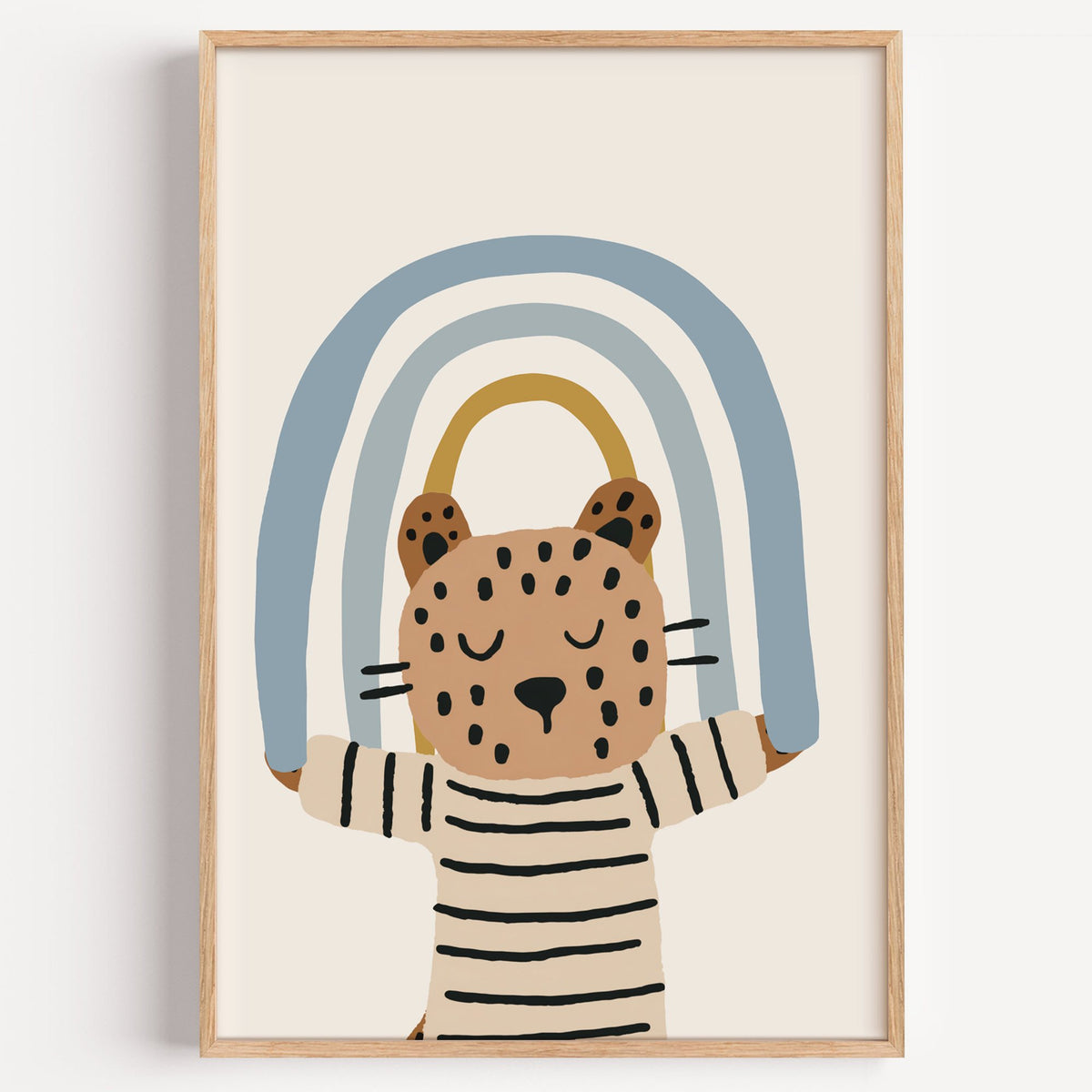 Leopard holding blue rainbow nursery print in a light oak frame on a plain white wall