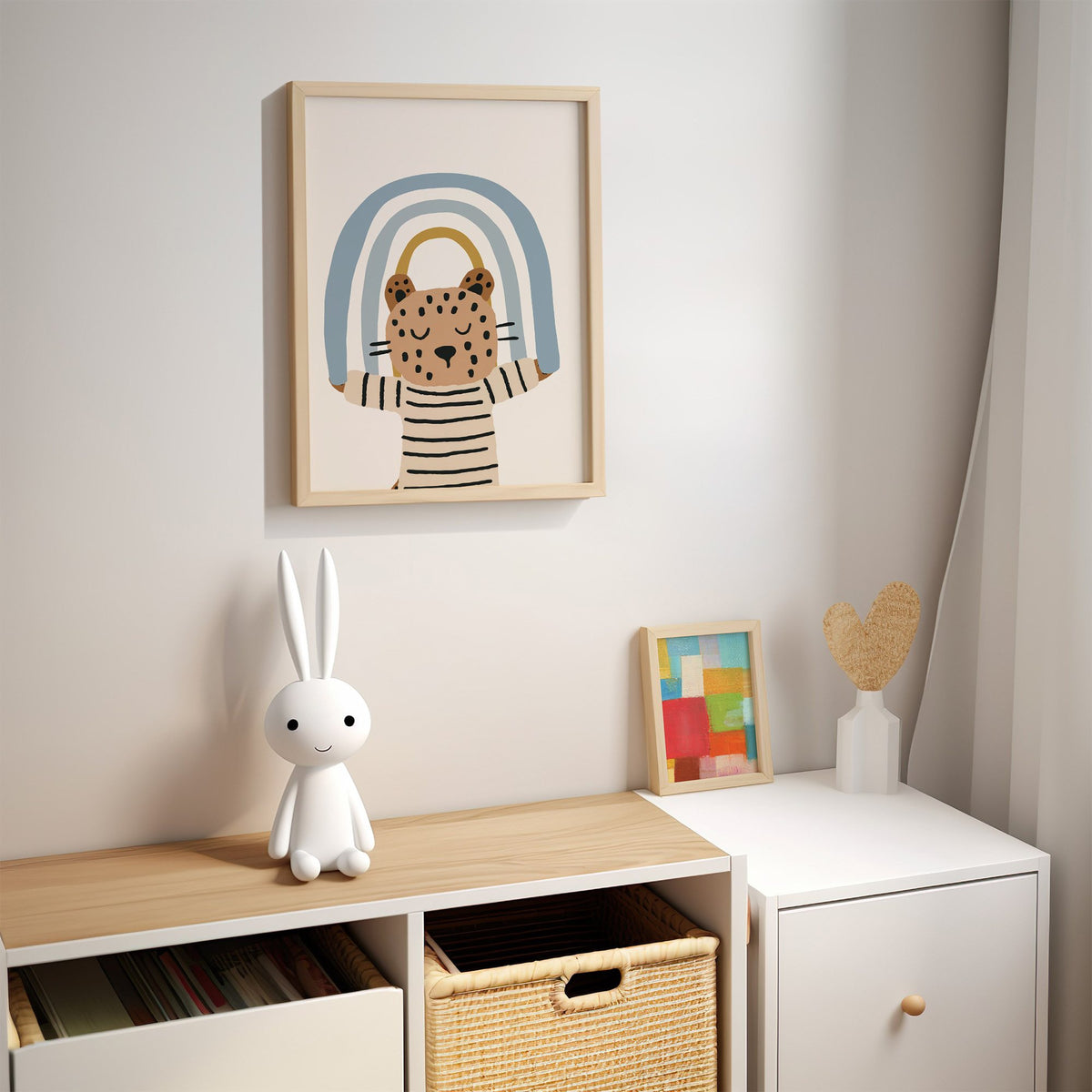 Leopard holding blue rainbow nursery print in an oak frame above a kids cubby shelf with a woven basket and bunny lamp