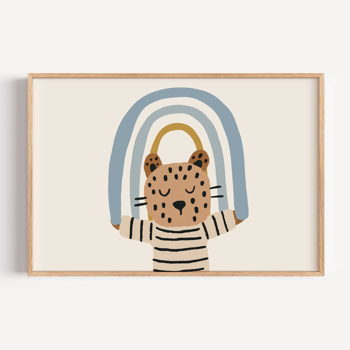 Landscape leopard holding blue rainbow nursery print in a light oak frame on a plain white wall