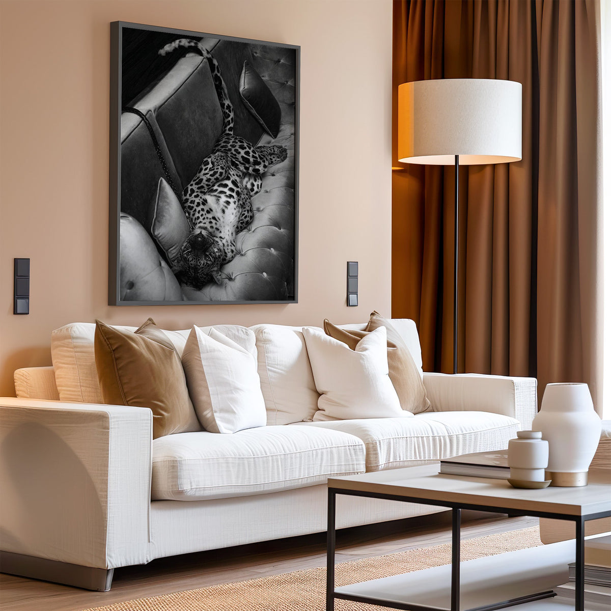 Leopard lying on its back on tufted sofa print in a black frame above a cream sofa on a blush living room wall