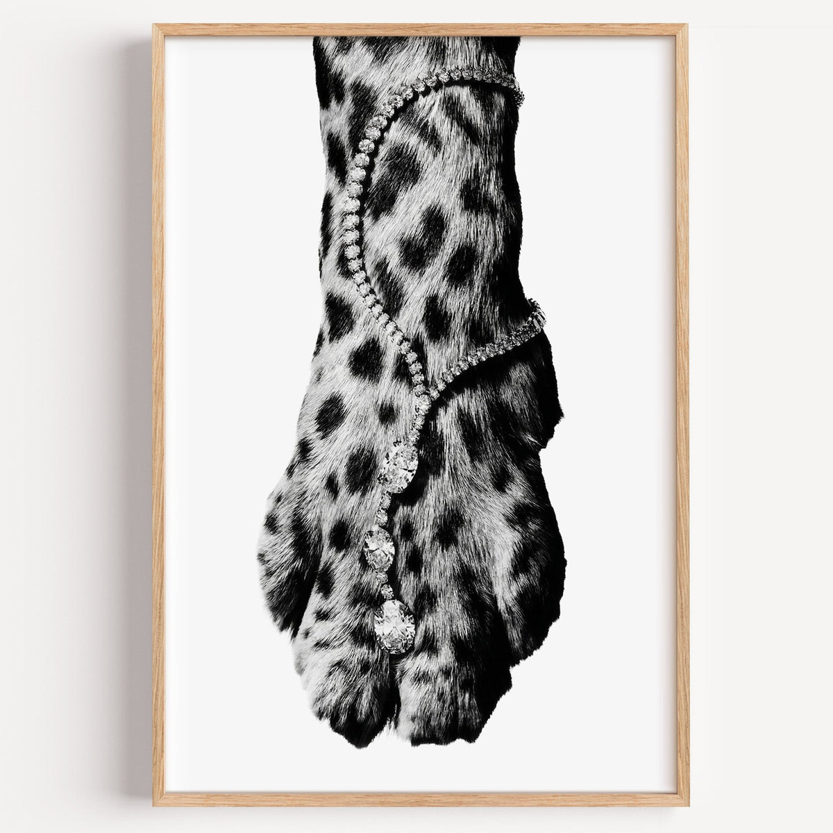 Leopard paw with sparkling stone anklet close-up print in a light oak frame on a plain white wall
