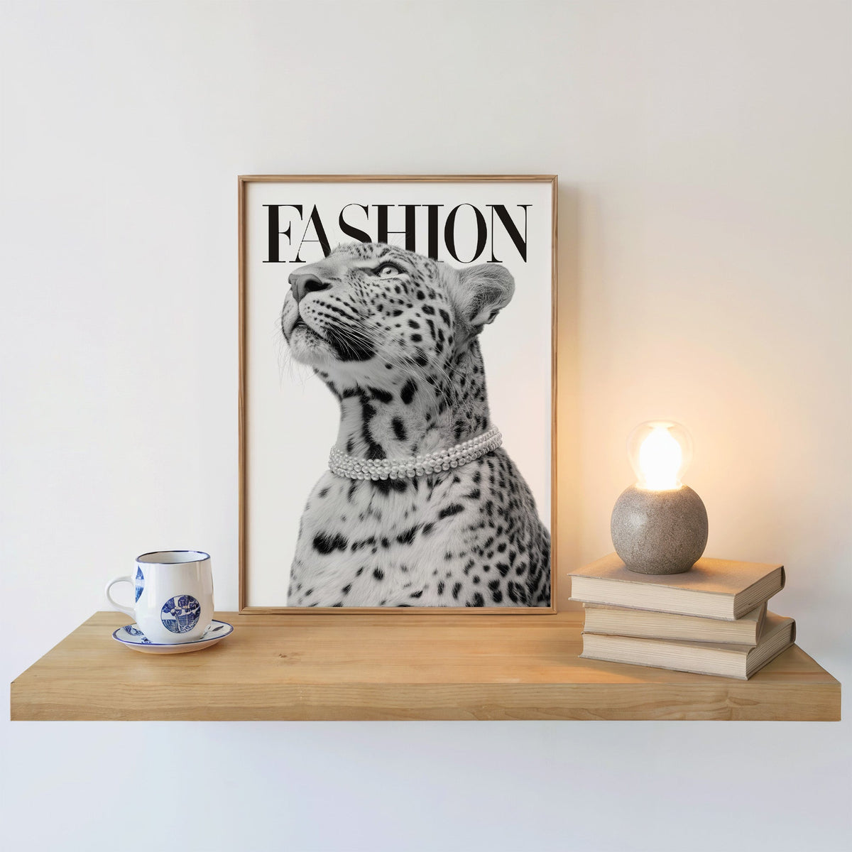 Leopard wearing pearl necklace fashion cover print in an oak frame on a floating shelf beside a glowing lamp