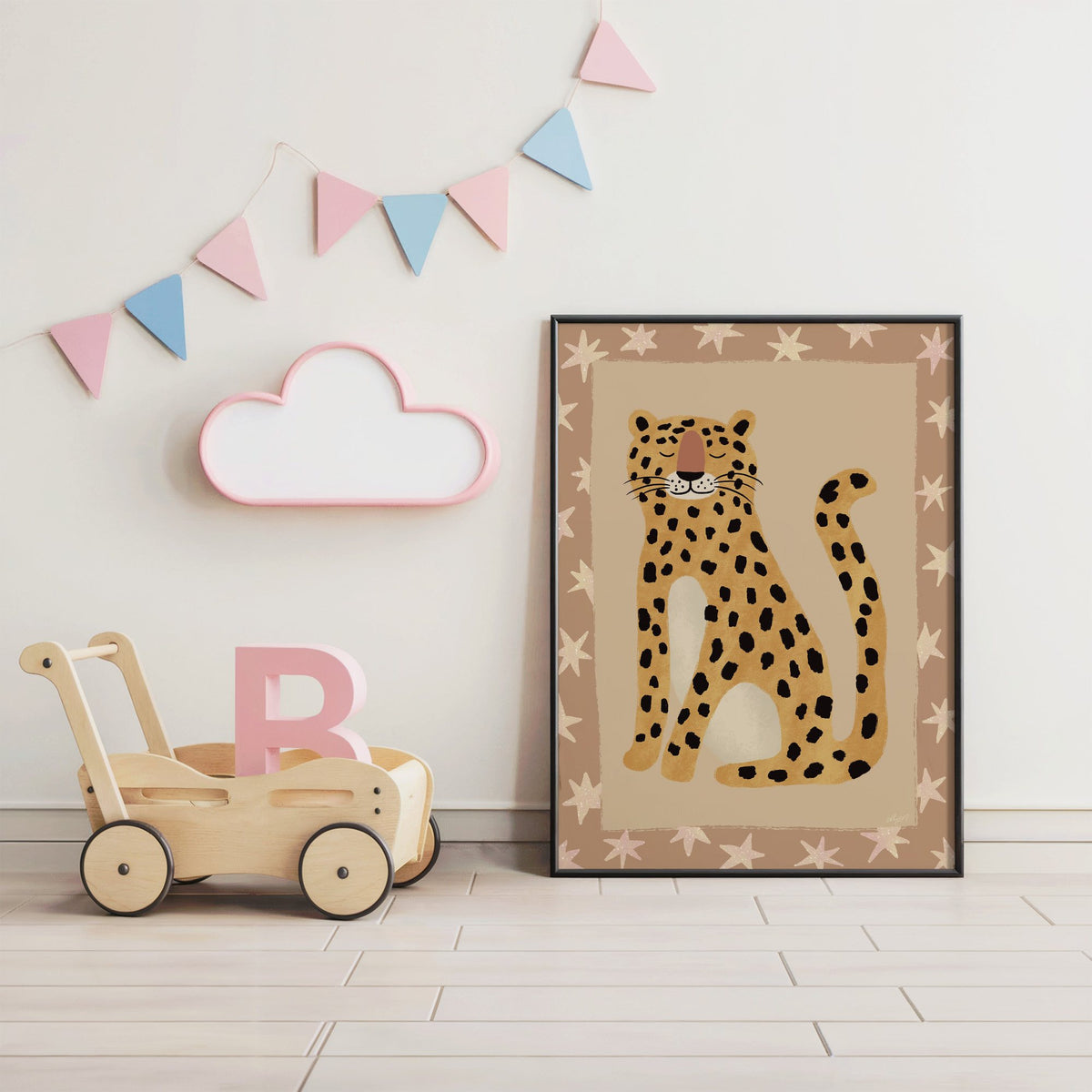 Smiling leopard with star border nursery print in a black frame under pastel bunting by a wooden baby walker