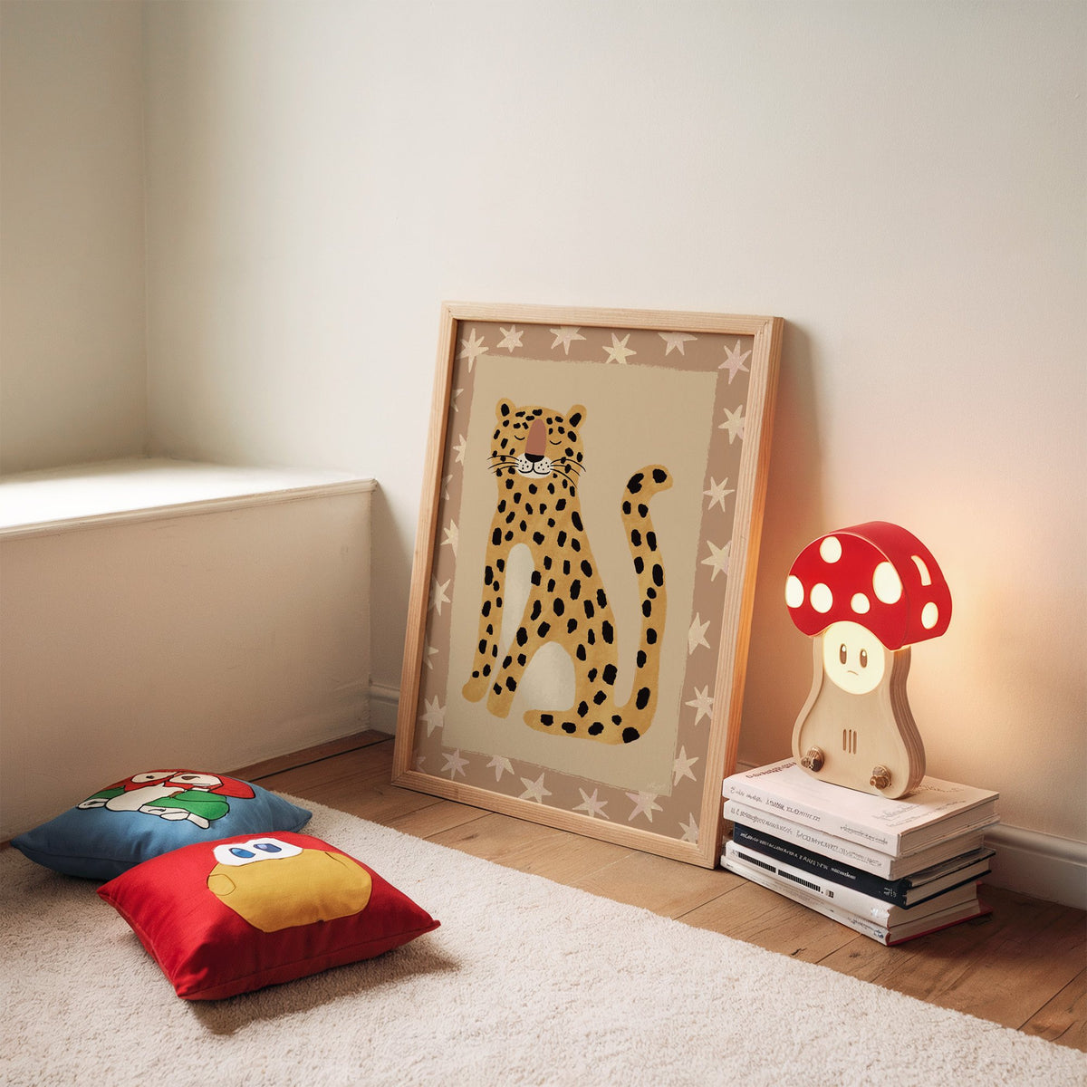 Smiling leopard with star border nursery print in an oak frame leaning on a rug beside a mushroom lamp and floor cushions