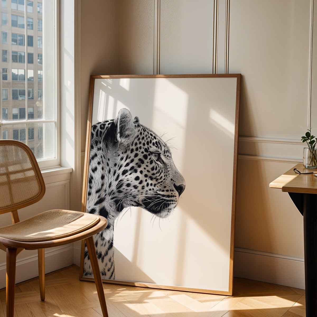 Text-free leopard profile on clean white background print in an oak frame leaning in a sunlit corner beside a cane chair
