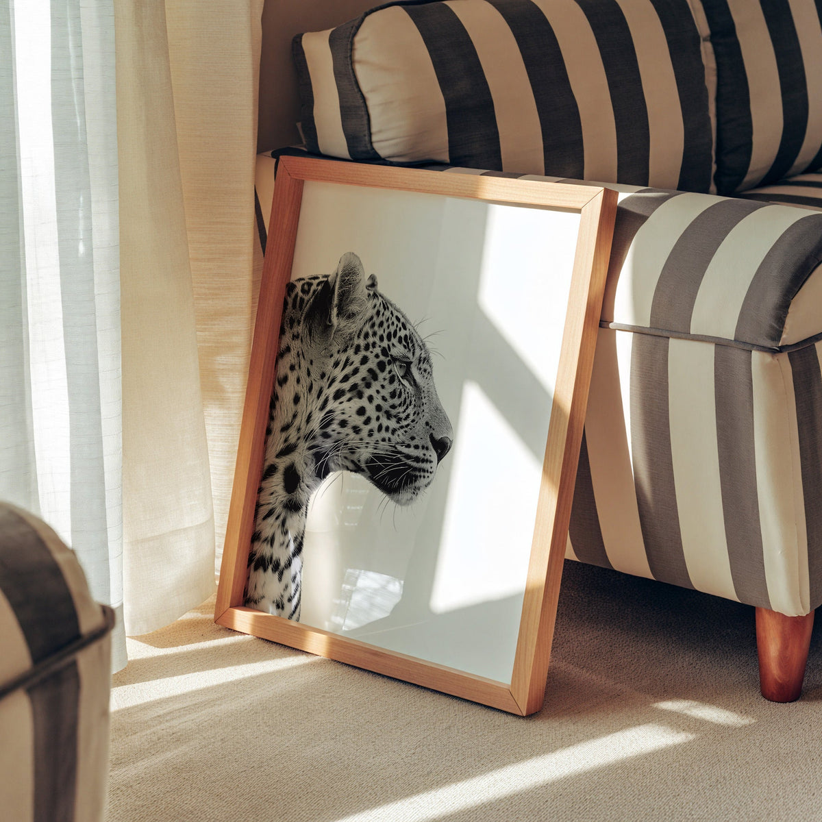 Text-free leopard profile on clean white background print in a pine frame leaning against a striped armchair